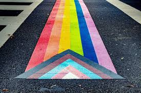 A pride progress flag painted on a street crosswalk